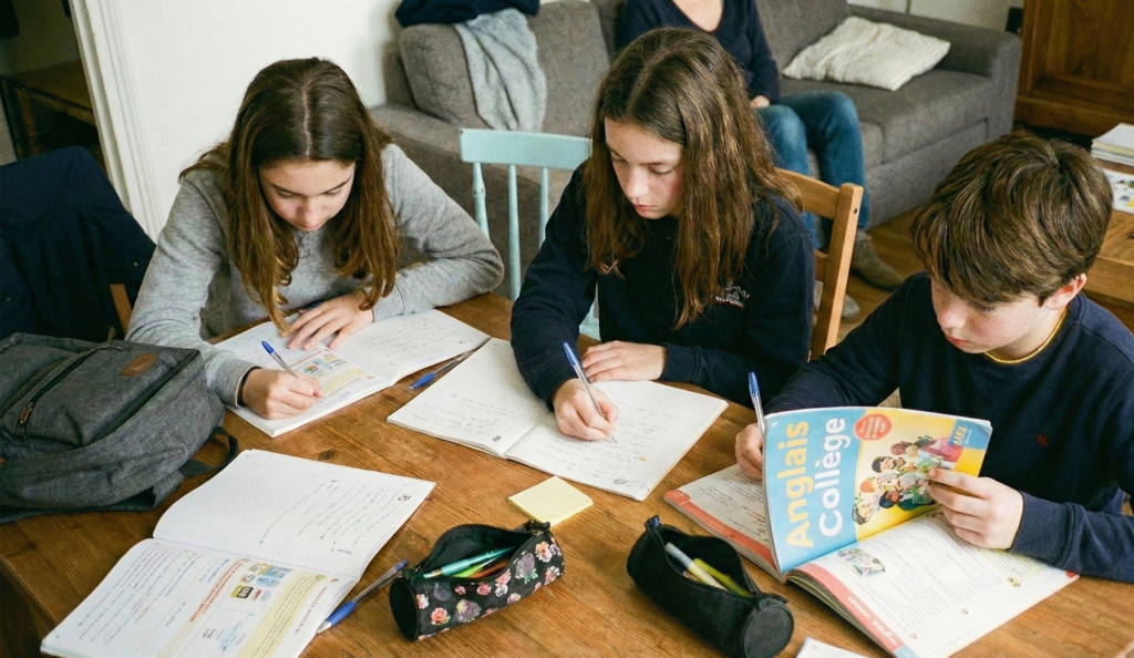 Collégiens travaillant l’anglais ensemble autour d’une table, dans un cadre familial et studieux
